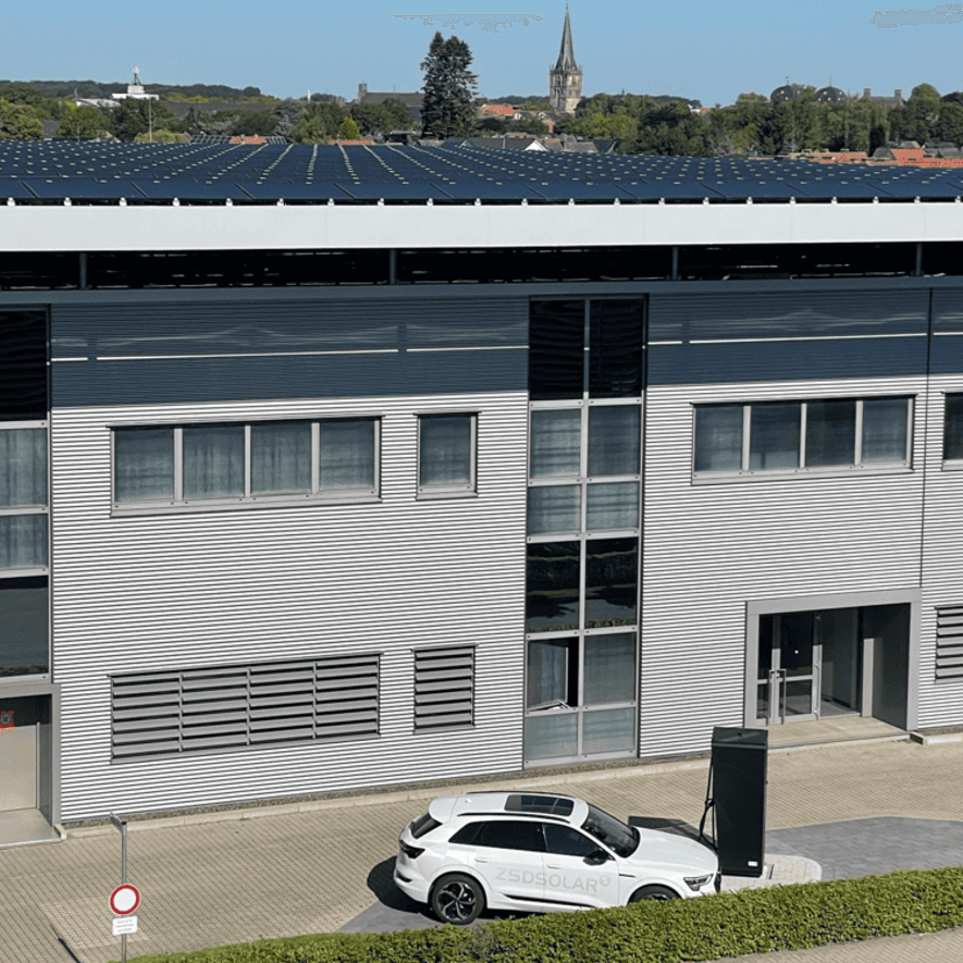 Ein weißes Auto wird vor einem Haus aufgeladen