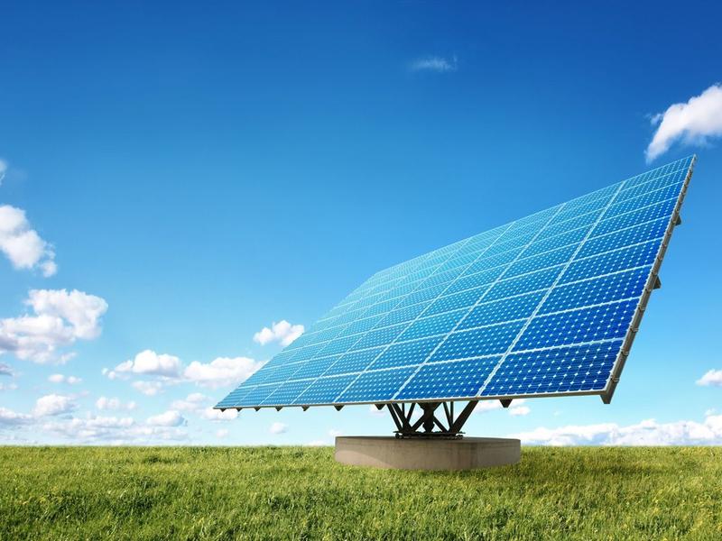 Eine Photovoltaik auf einer grünen Wiese bei einem klaren blauen Himmel